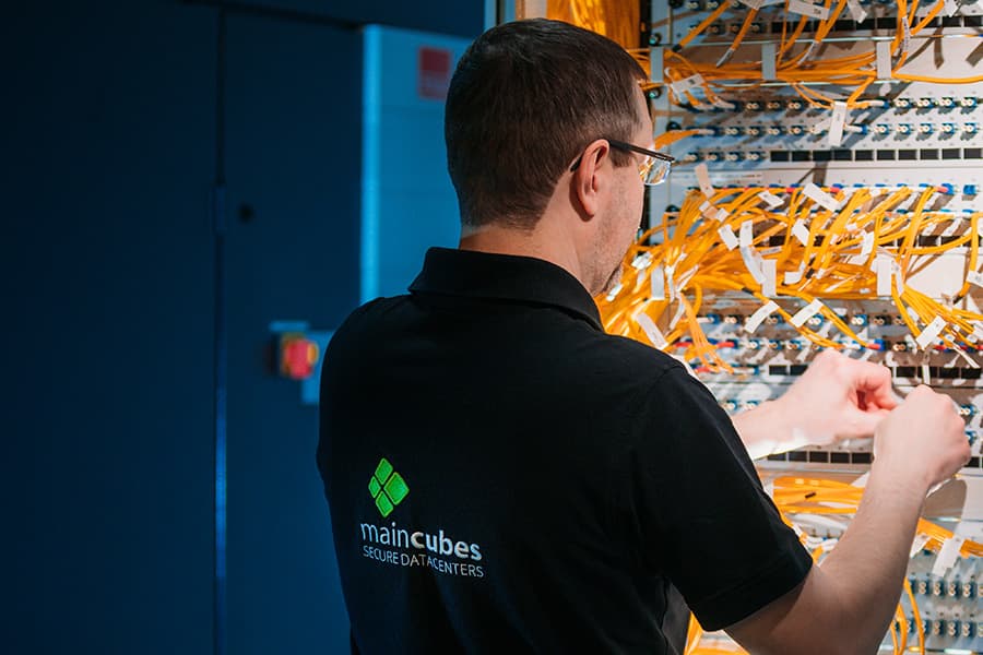 Techniker von maincubes schließt Glasfaserkabel an einem Patchfeld an